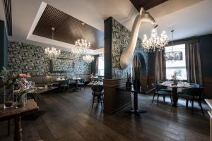 une salle à manger avec des tables, des chaises et des lustres dans l'établissement Post Hotel - Tradition & Lifestyle Adults Only, à San Candido