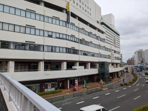 ein hohes weißes Gebäude an der Straßenseite in der Unterkunft Smile Hotel Tokushima in Tokushima