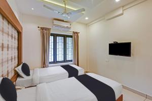 um quarto de hotel com duas camas e uma televisão em Hotel O AURA RESIDENCY em Kannur