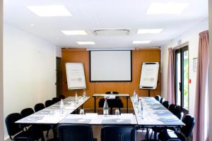 uma sala de conferências com uma mesa longa com cadeiras e um ecrã em Campanile Annecy - Cran Gevrier em Annecy