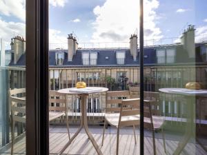 d'un balcon avec une table, des chaises et une fenêtre. dans l'établissement Hotel Maison Hamelin Paris - Handwritten Collection, à Paris