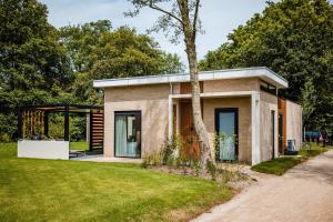 a small brick house with a tree at Recreatiewoning 'Steenpatrijs' in Voorthuizen