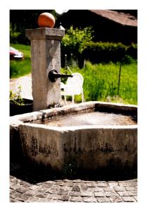 une fontaine d'eau avec une chaise blanche. dans l'établissement B&B Château la Grande Riedera, 