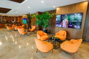 una sala de espera con sillas naranjas y TV en Byblos Hotel, en Abiyán