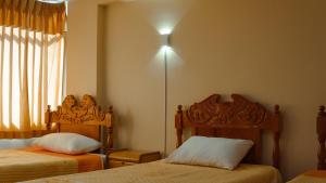 a bedroom with two beds and a light on the wall at Rama Inn Hostal in Puno