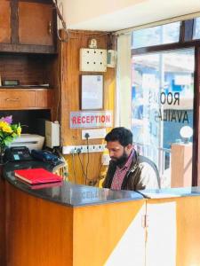 Ein Mann, der am Schalter eines Versenders sitzt. in der Unterkunft Hotel mystique inn ooty in Udagamandalam