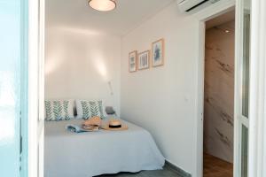 a white room with a bed with a hat on it at Nikis Village in Poros