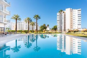 una piscina con palme e edifici di THB San Fermín a Benalmádena