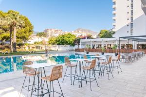 un patio con tavoli e sedie accanto alla piscina di THB San Fermín a Benalmádena