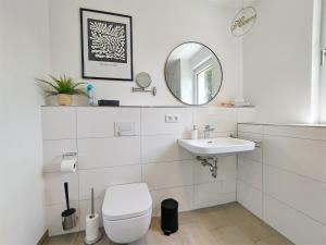 bagno bianco con servizi igienici e lavandino di CityVibe Apartment für bis zu 4 a Erlangen