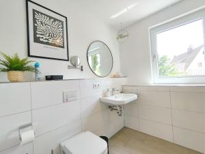 bagno bianco con lavandino e specchio di CityVibe Apartment für bis zu 4 a Erlangen