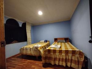 a bedroom with two beds and a blue wall at Inti Ut'ha in Puno