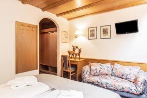 een slaapkamer met een bed, een bank en een bureau bij Hotel Meida in Pozza di Fassa