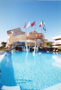 un bâtiment avec des drapeaux au-dessus d'une piscine d'eau dans l'établissement Hotel Poseidon, à Terracine