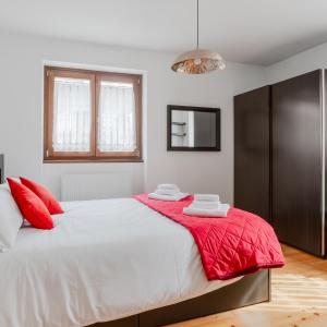 a bedroom with a large white bed with red pillows at Lioda Roccia in Masariè