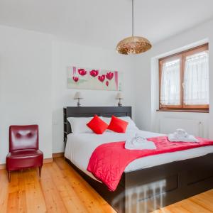 a bedroom with a bed with red pillows and a chair at Lioda Roccia in Masariè