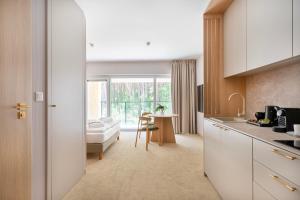 a kitchen with white cabinets and a living room at Sea Shell Apartments Łukęcin in Łukęcin