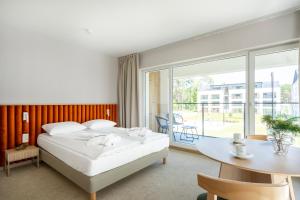 a bedroom with a bed and a desk and a table at Sea Shell Apartments Łukęcin in Łukęcin