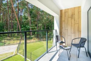 two chairs and a table on a balcony with trees at Sea Shell Apartments Łukęcin in Łukęcin