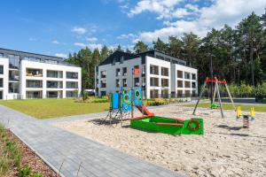 a playground in the sand in front of a building at Sea Shell Apartments Łukęcin in Łukęcin