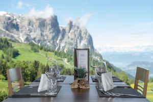 una mesa con copas de vino y vistas a la montaña en Berghotel Zorzi, en Alpe di Siusi