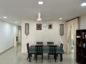 mesa de comedor con sillas y reloj en la pared en Maryam Homestay Putrajaya17, en Putrajaya