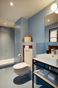 a blue bathroom with a toilet and a sink at Edgar Suites Montrouge in Montrouge