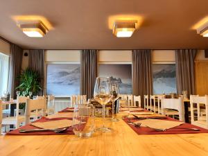 uma sala de jantar com uma longa mesa com copos de vinho em Hotel Rododendro Val di Fassa em Campitello di Fassa