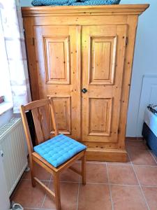 a wooden chair with a blue seat in front of a door at Harzgeist in Goslar