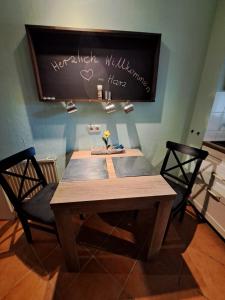 a wooden table with two chairs and a chalkboard on the wall at Harzgeist in Goslar