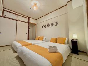 1 Schlafzimmer mit 2 Betten mit orangefarbener und weißer Bettwäsche in der Unterkunft Neighbor's Hotel 広島駅北口 in Hiroshima