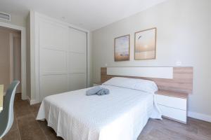 a bedroom with a white bed with a wooden headboard at Acogedor Refugio con Terraza in Alcalá de Henares