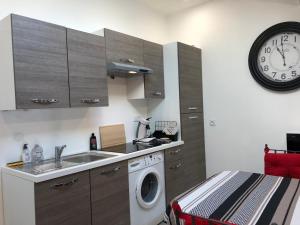 a kitchen with a washing machine and a clock at Le Logis de Virginie - climatisé in Rochefort