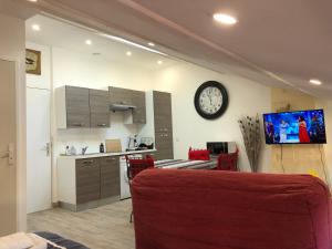 a kitchen with a clock on the wall and a red couch at Le Logis de Virginie - climatisé in Rochefort