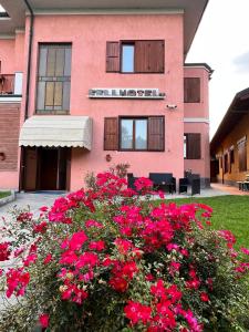 een roze gebouw met rode bloemen ervoor bij Fell Hotel in Susa