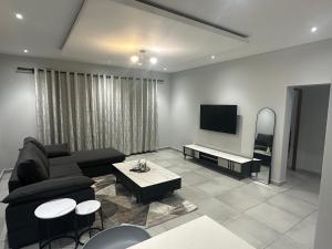 un soggiorno con divano e TV a schermo piatto di Mountain Drive Apartments a Mbabane