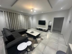 un soggiorno con divano nero e TV di Mountain Drive Apartments a Mbabane