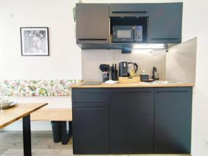 uma cozinha com armários pretos e uma mesa de madeira em Design-Apartmenthaus für bis zu 12, modern, Dachterrasse, Grill, ruhige Lage, Disney plus, Wii, LAN und WLAN em Nuremberga