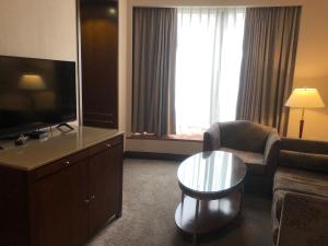 een woonkamer met een televisie, een stoel en een tafel bij Monarch Plaza Hotel in Taoyuan