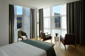 une chambre d'hôtel avec un lit, des chaises et des fenêtres dans l'établissement Abrigo da Montanha Hotel Rural, à Sabugueiro