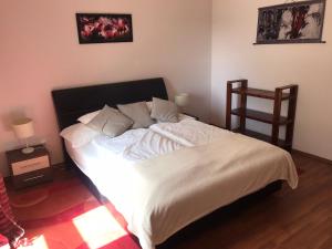 a bedroom with a bed with white sheets and a chair at Feng Shui Wellness Apartmanház Hévíz in Hévíz