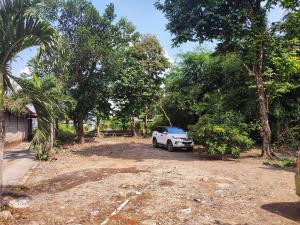 un coche blanco aparcado en un terreno con árboles en Happy Syariah Hotel near Jombor Mitra RedDoorz, en Sleman