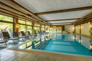 a swimming pool with chairs and tables in a building at Ringhotel Mönch`s Waldhotel in Unterreichenbach