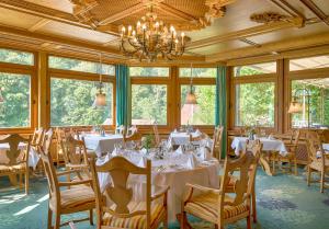 a dining room with tables and chairs and windows at Ringhotel Mönch`s Waldhotel in Unterreichenbach