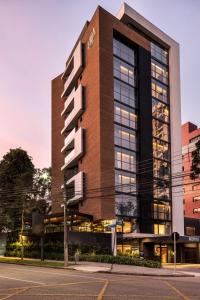 Un edificio alto con un reloj a un lado. en Nomaa Hotel, en Curitiba