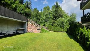 a backyard with a stone wall and a grass yard at Villa Dolomiti in Ortisei