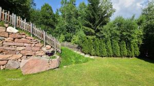 a fence next to a stone wall and trees at Villa Dolomiti in Ortisei