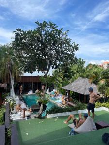 un gruppo di persone seduti intorno alla piscina in un resort di Nyaman Hostel a Canggu