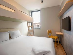 - une chambre avec un lit, une télévision et une chaise dans l'établissement ibis budget Leuven Centrum, à Louvain