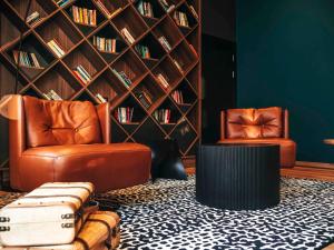 a library with two leather chairs and a book wall at ibis Styles Wałbrzych in Wałbrzych